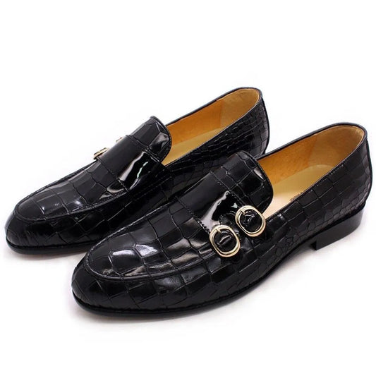 Black crocodile pattern men's dress loafers with gold buckles on a white background