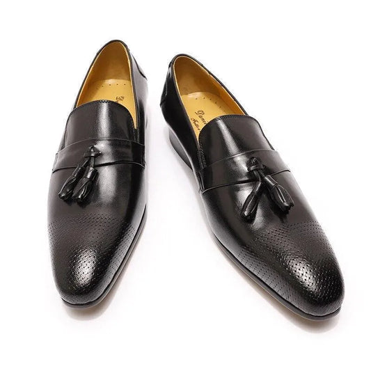 Black leather tassel loafers for men with perforated toe on white background