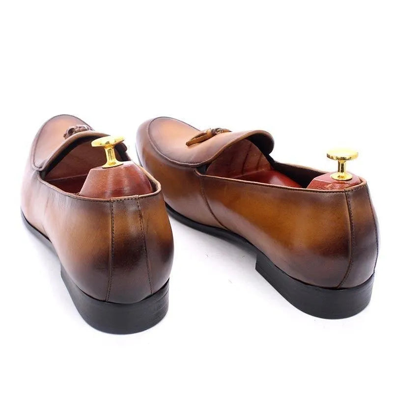 Brown leather men's tassel loafers with shoe trees, black soles, white background
