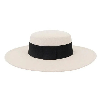Beige derby fedora hat with wide black band and flat brim on white background