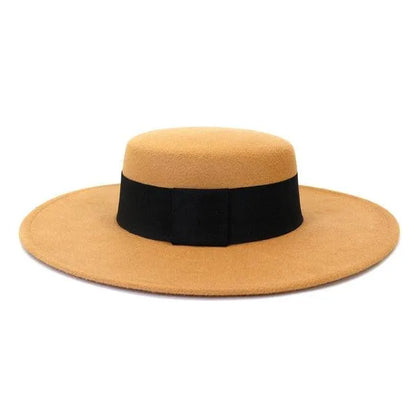 Tan derby fedora hat with wide black band and flat brim on white background
