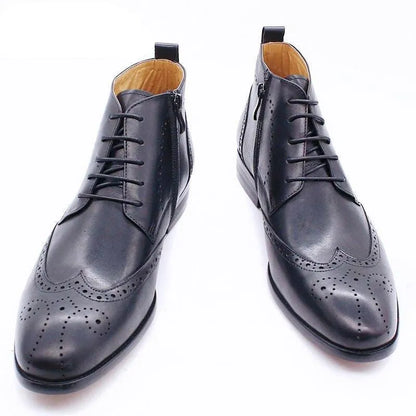 Black formal leather ankle boots with brogue detailing on white background
