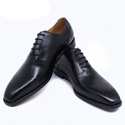 Black leather lace-up dress shoes for men with brogue details on white background.