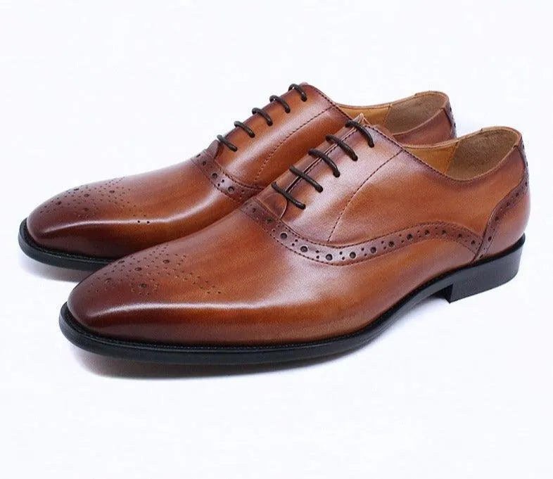 Brown leather lace-up men's dress shoes with brogue detailing on a white background