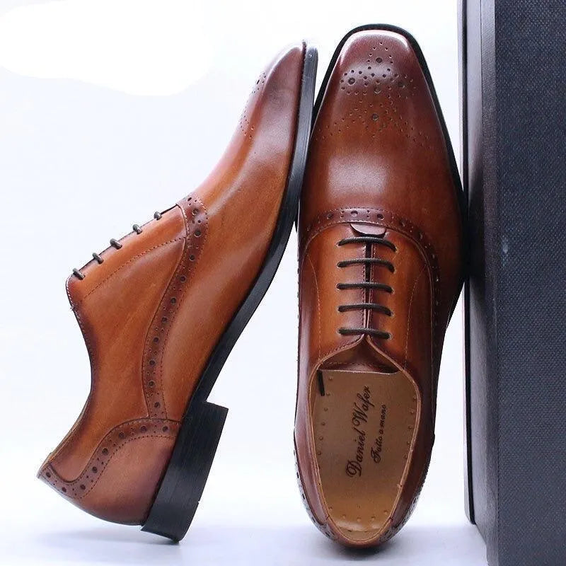 Brown leather lace-up men's dress shoes with brogue details on a white background
