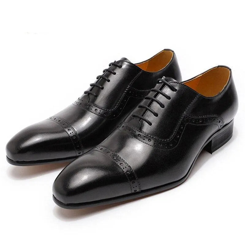 Black leather men's dress shoes with pointed toe and brogue detailing on white background