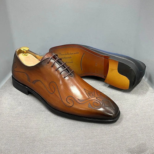 Brown leather men's dress shoes with engraved swirl design, black soles, and laces.