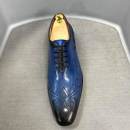 Blue leather men's dress shoe with black patterns and laces on a gray fabric surface