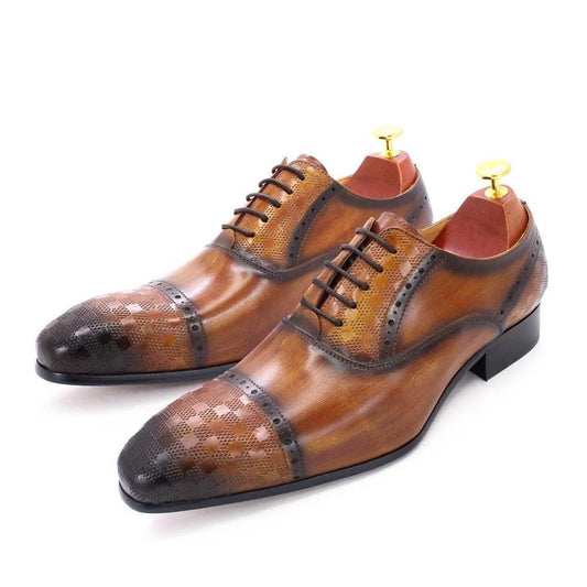 Brown leather men's lace-up dress shoes with decorative perforations, isolated on white