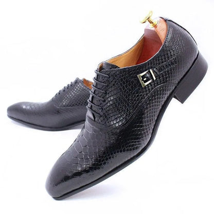 Black men's dress shoes with reptile texture, buckle detail, and leather soles on white background.