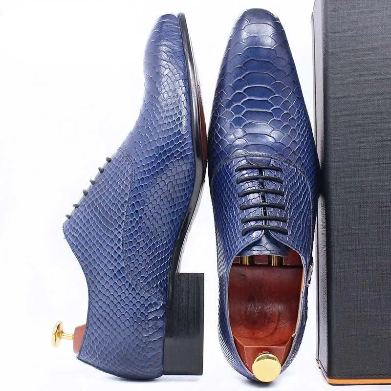 Blue snakeskin textured men's dress shoes with black laces beside a black box