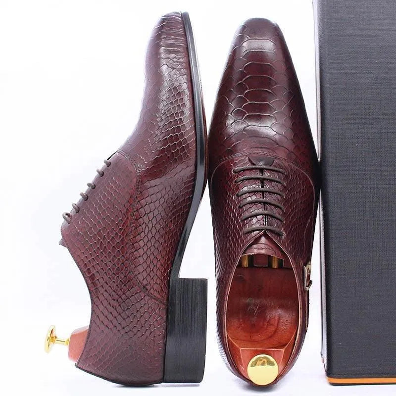 Men's burgundy dress shoes with snakeskin pattern, leather sole, and wooden shoe trees