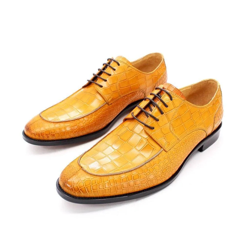 Men's tan crocodile pattern dress shoes with black laces on white background