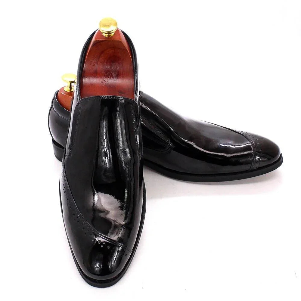 Glossy black slip-on dress shoes for men with wood shoe trees on white background