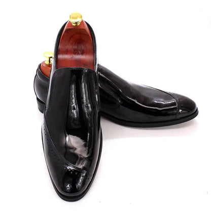 Glossy black slip-on dress shoes for men with wood shoe trees on white background