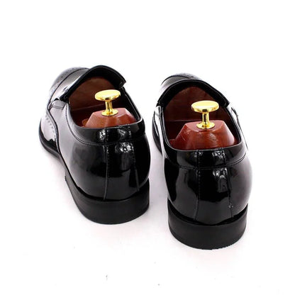Black glossy leather men's slip-on dress shoes with wooden shoe trees on white background
