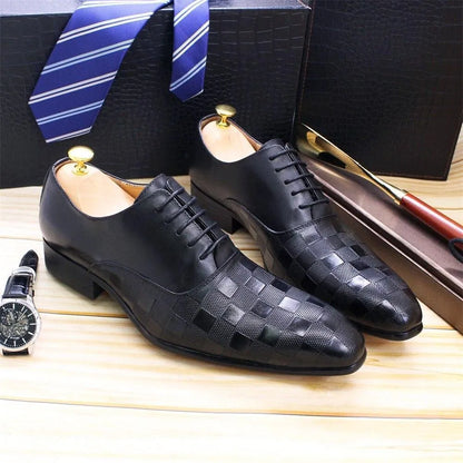 Black checked leather men’s dress shoes with laces on wooden surface, blue striped tie