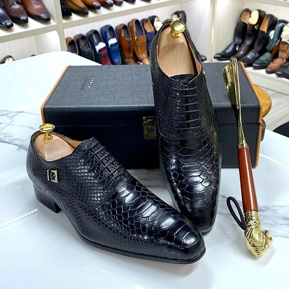 Black crocodile pattern men’s dress shoes displayed on a marble table with shoe box