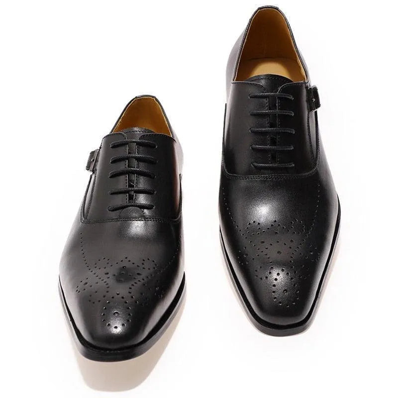 Black leather men's dress shoes with classic brogue detailing on white background