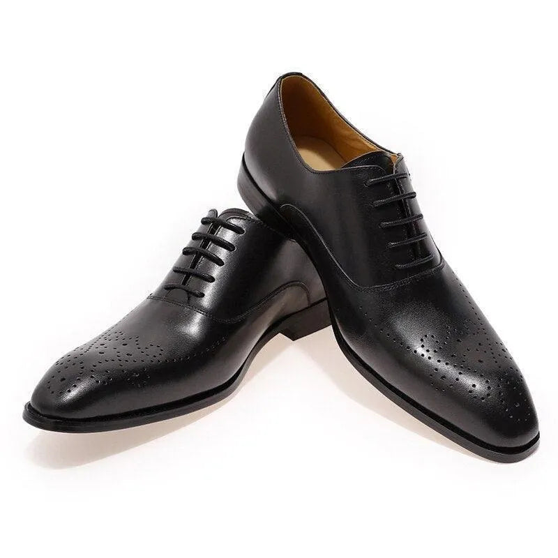 Black leather men's dress shoes with brogue detailing on white background
