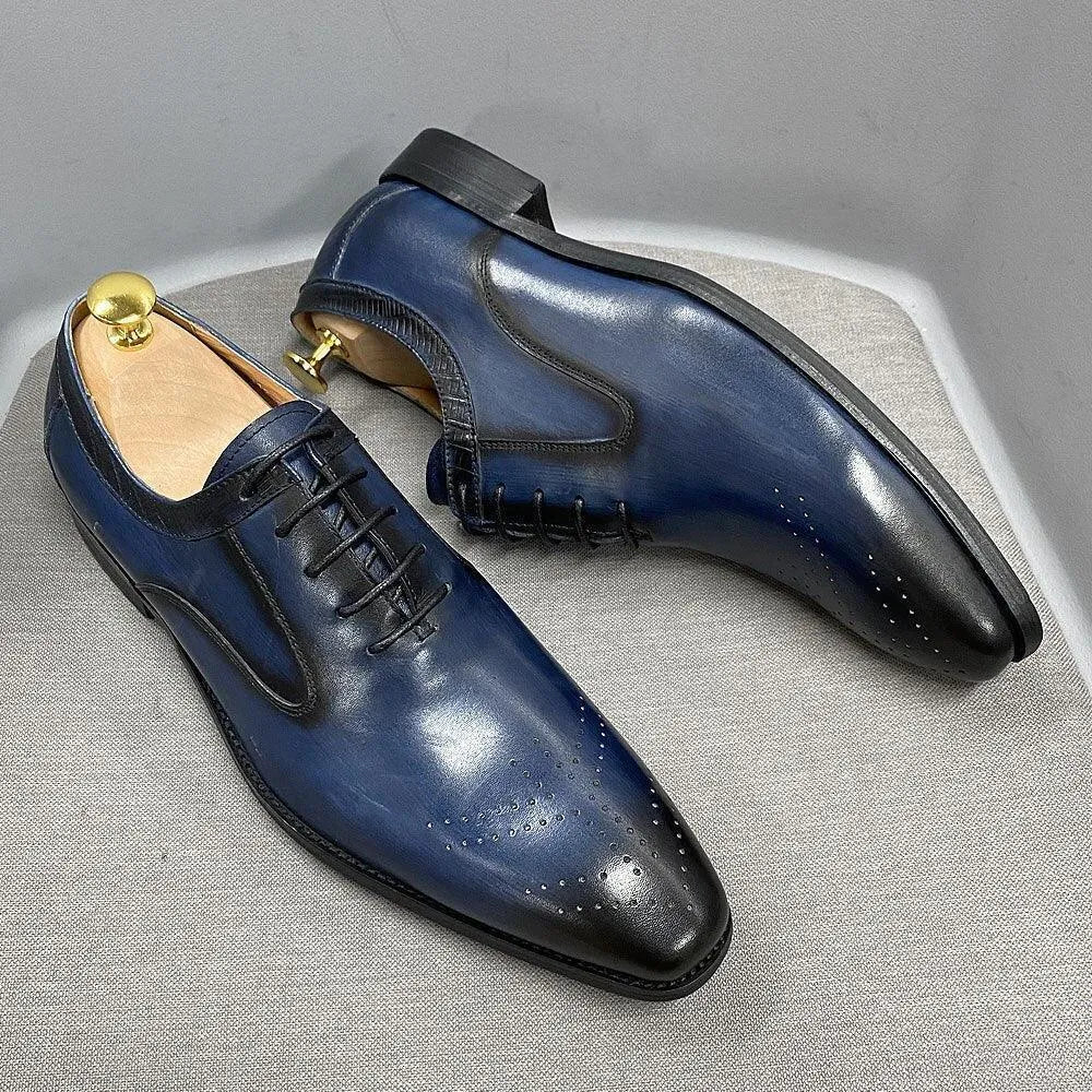 Glossy navy blue men's dress shoes with black toe cap, lace-up, on light fabric surface