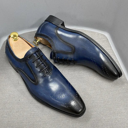 Glossy navy blue men's dress shoes with black toe cap, lace-up, on light fabric surface
