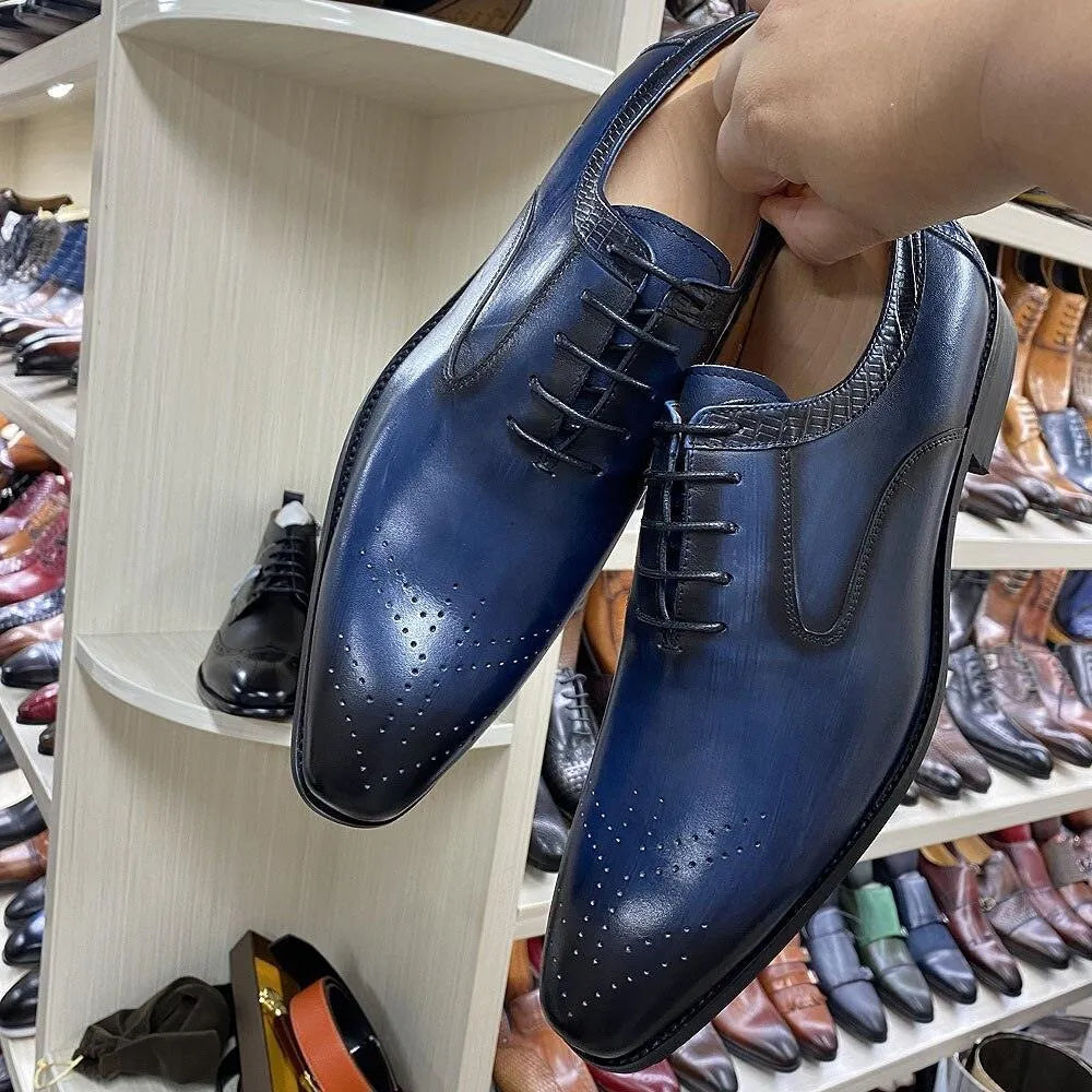 Glossy blue lace-up men's dress shoes with perforated toe, displayed in a shoe store.