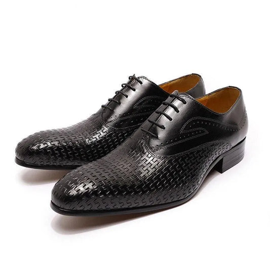 Black leather dress shoes with pointed toes and textured woven pattern on white background