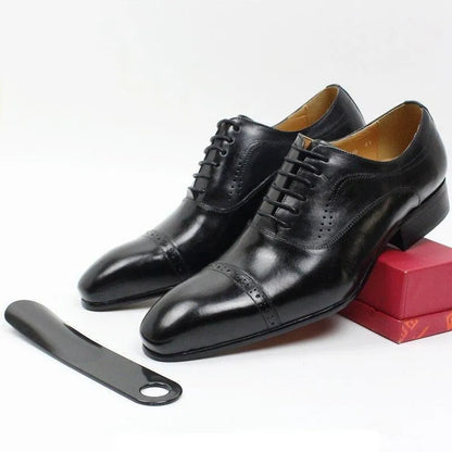 Black leather men's dress shoes with lace-up design and shoehorn on white background