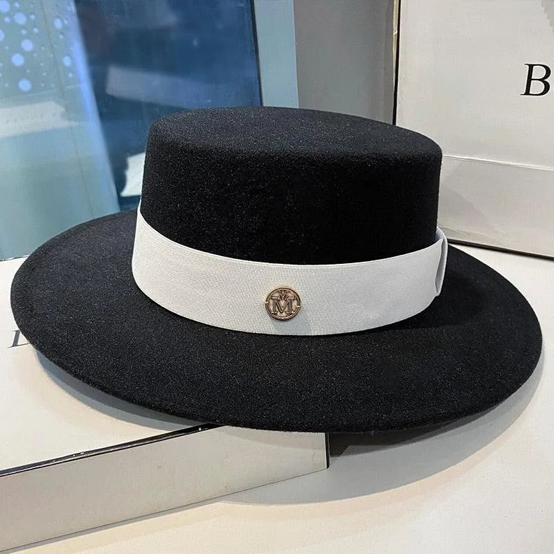 Elegant black flat-top fedora hat for women with white band and gold emblem