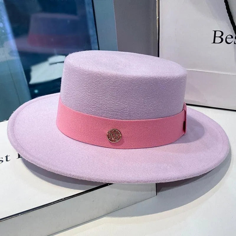 Elegant women's lavender flat-top fedora hat with pink band and gold accent, displayed indoors.