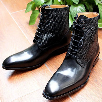 Black leather ankle boots with textured uppers on wooden floor, green plant in background