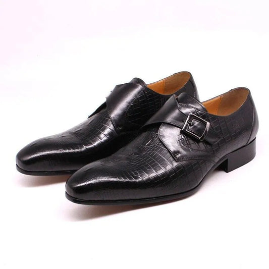 Black men's leather dress shoes with a crocodile pattern and side buckles on white background