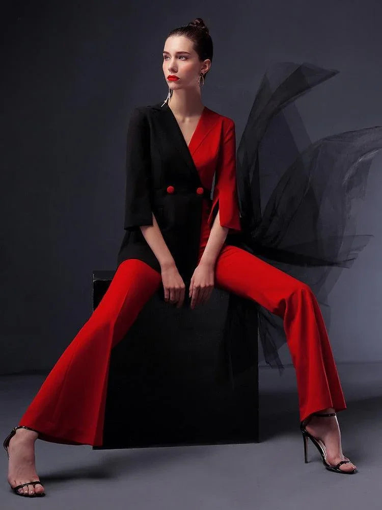 Woman in red and black pantsuit with detachable black veil, sitting on black box