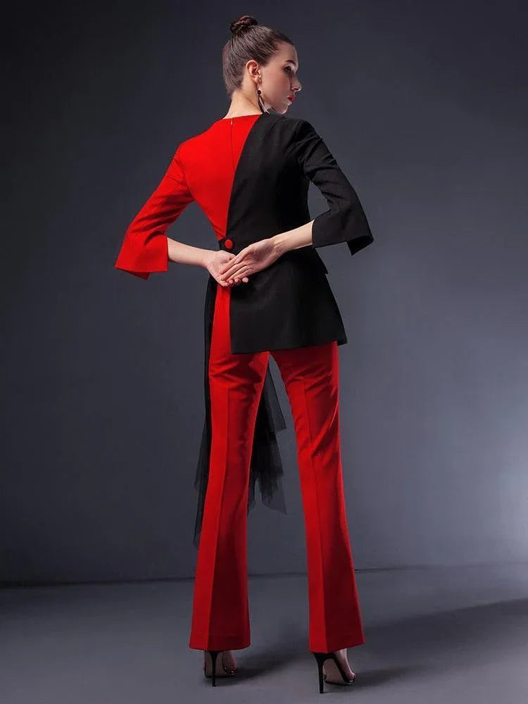 Woman wearing red and black pantsuit with detachable veil, standing in studio