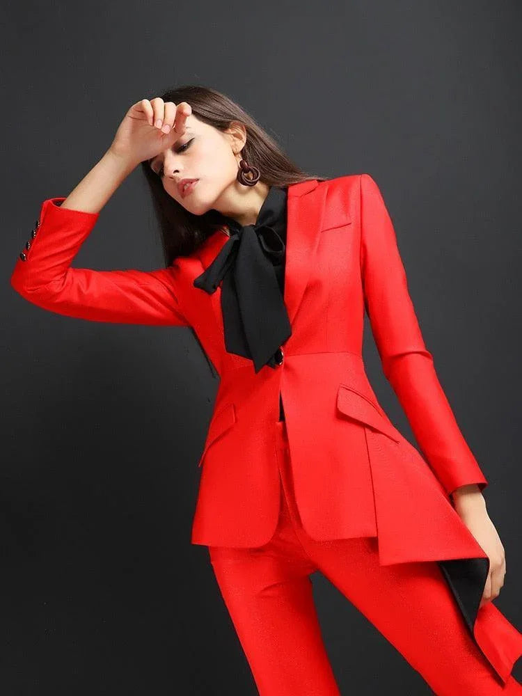 Woman in stylish red flared pant suit with black bow tie, posing against a dark background