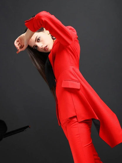 Woman posing in a red flared pant suit against a plain black background