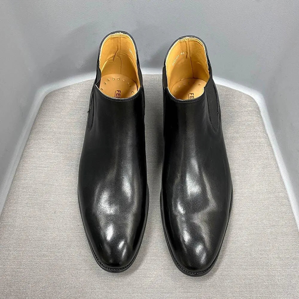 Black leather ankle dress boots with tan lining on a gray surface