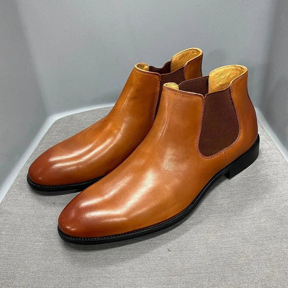 Tan leather ankle dress boots with elastic side panels on a gray display surface