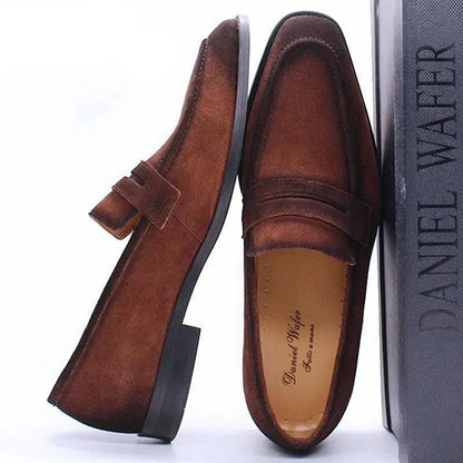 Brown suede men's dress loafers with a low heel, displayed beside a Daniel Wafer shoe box